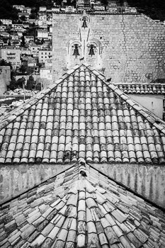 "Holy Roost" fine art black and white photograph by Nat Coalson. Beneath three bells in a tower, pigeons sit atop an ancient church in the Old Town of Dubrovnik, Croatia. Black and white photo. Prints available, for details click the Purchase link above.